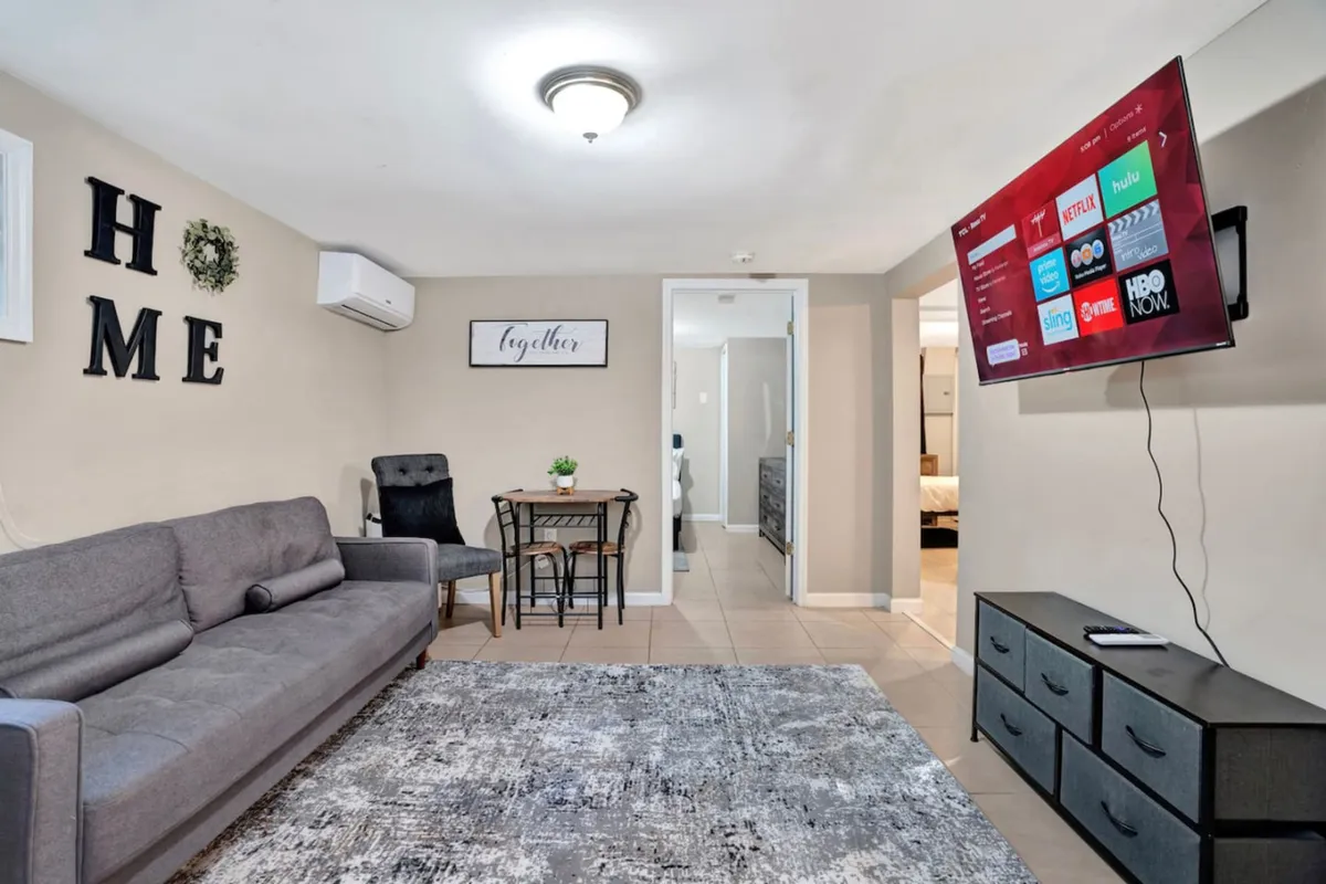 A cozy and stylish interior scene with a sofa and TV in the living area, and a visible dining table nearby. The arrangement fosters easy social interaction and creates a warm, inviting ambiance.