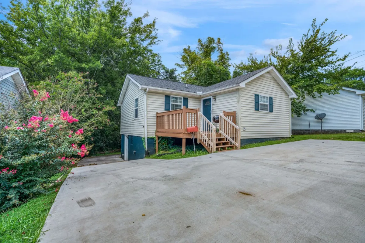This image features a welcoming front porch surrounded by flowering bushes and a clear view of the driveway. The inviting porch is a natural transition point between the private, tranquil villa-style apartment and the vibrant downtown scene just steps away.