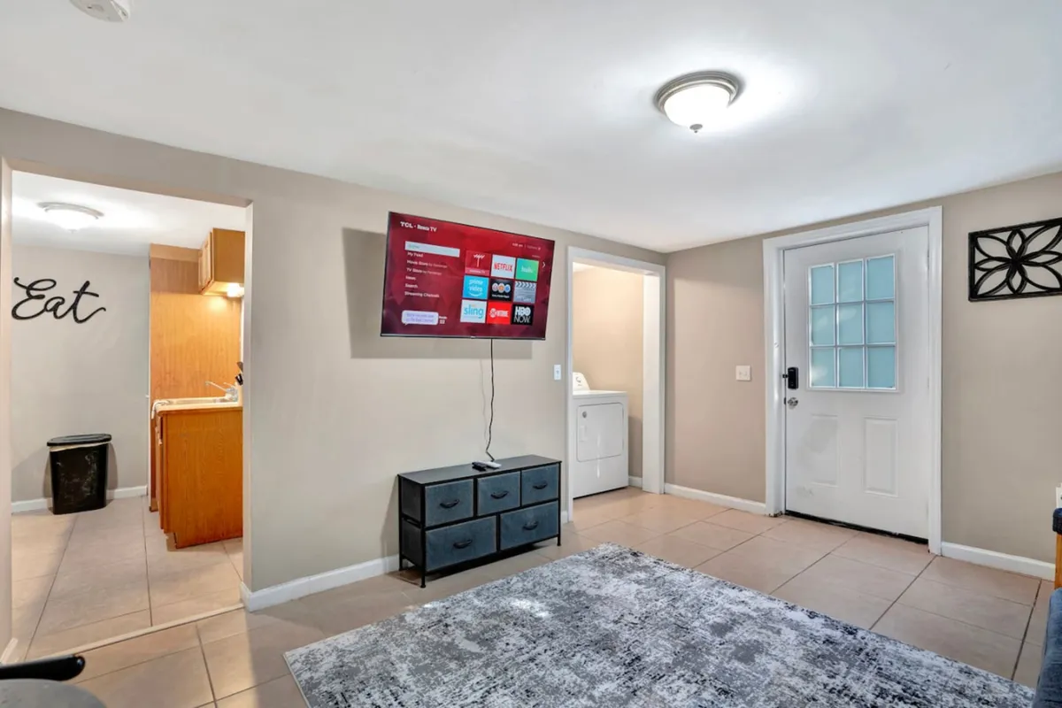 A comfortable living space with a television, a soft rug, and a visible doorway inviting movement between rooms. The scene captures moments of socializing, watching TV, and enjoying family meals, suggesting a hub for relaxation between adventures.