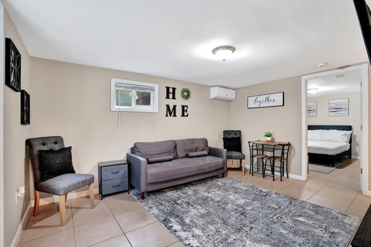 The image showcases a stylish, cozy living area with a plush sofa, inviting wall decor, and a dining table perfect for sharing meals. The room exudes warmth and comfort, with soft lighting and modern touches that create a relaxing atmosphere ideal for unwinding or gathering with loved ones.