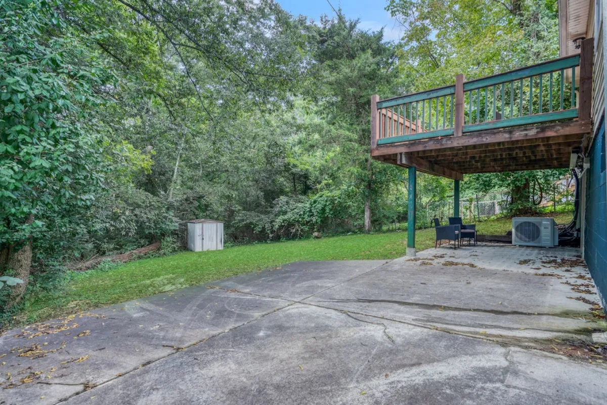 A peaceful backyard deck surrounded by lush greenery, with space for outdoor dining or gatherings. The patio area hints at opportunities for morning coffees, evening get-togethers, or even enjoying takeout from local restaurants in a tranquil outdoor setting.